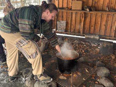 Voksen laver mad på bål